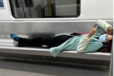 女子横躺玩手机 小伙“地铁盖被” 网友点赞：这招妙啊